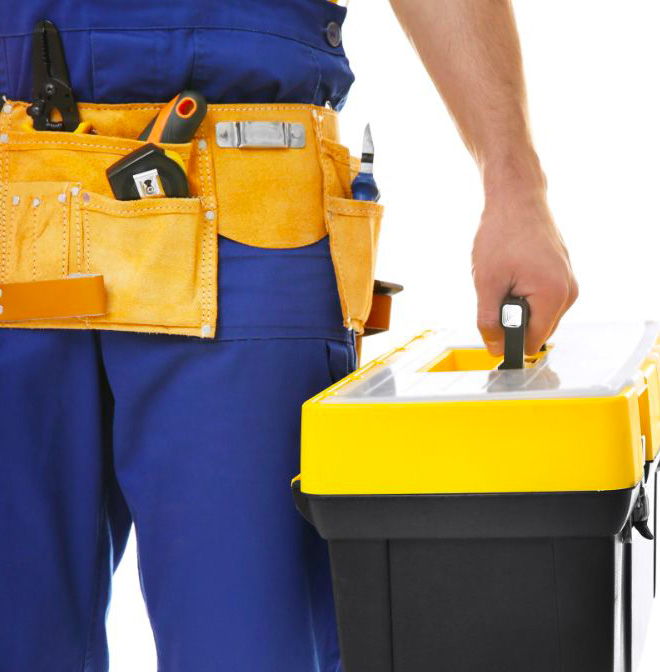 Un technicien en uniforme bleu porte une boîte à outils jaune